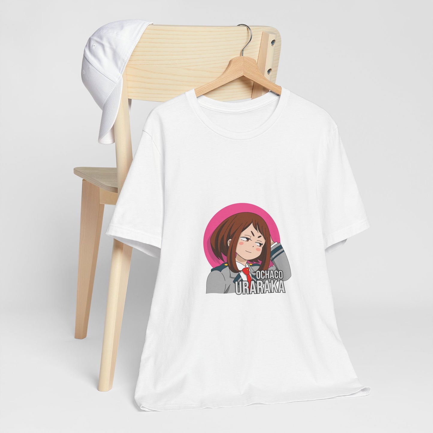 Alt: Gravity Hero Academy Anime Shirt on white, hanging on chair with cap, lifestyle display by Snapping Turtle Gallery