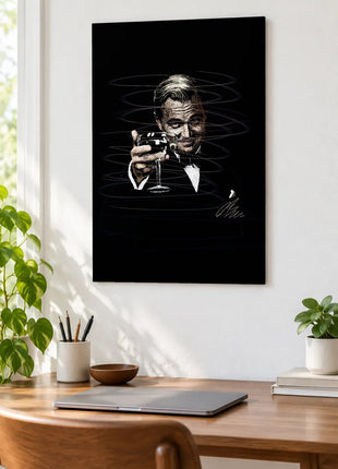 A Toast in the Dark acrylic wall art displayed above a wooden desk with a laptop, plants and books against a white wall.