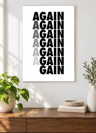 Again Becomes Gain acrylic wall art displayed above a wooden console with plants and books against a white wall.