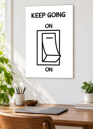 Always Switched On acrylic wall art displayed above a wooden desk with a laptop, plants and books against a white wall.