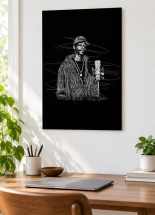 At the Studio Microphone acrylic wall art displayed above a wooden desk with a laptop, plants and books against a white wall.