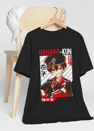 Black Hanako-kun graphic T-shirt on a wooden hanger beside a chair.