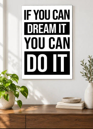 Dream It Do It acrylic wall art displayed above a wooden console with plants and books against a white wall.