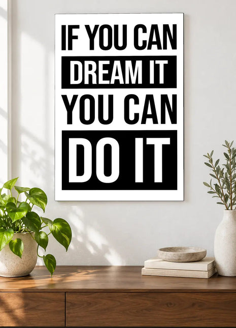 Dream It Do It acrylic wall art displayed above a wooden console with plants and books against a white wall.