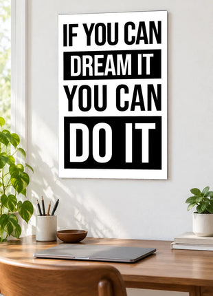 Dream It Do It acrylic wall art displayed above a wooden desk with a laptop, plants and books against a white wall.