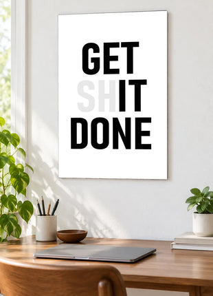 Get It Done acrylic wall art displayed above a wooden desk with a laptop, plants and books against a white wall.