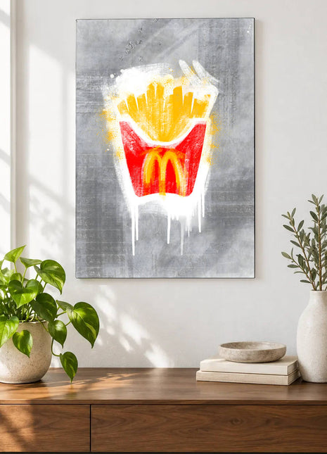 Golden fries in a red arches carton with white paint drips on gray displayed above a console table in a room setting