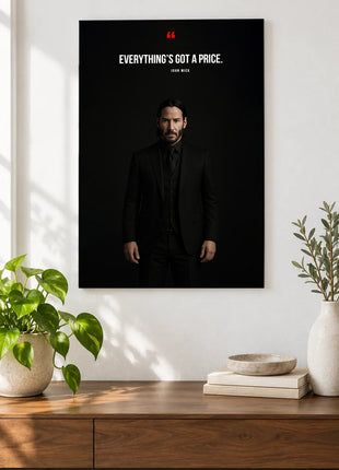John Wick Everything Has a Price acrylic wall art displayed above a wooden console with plants and books against a white wall.