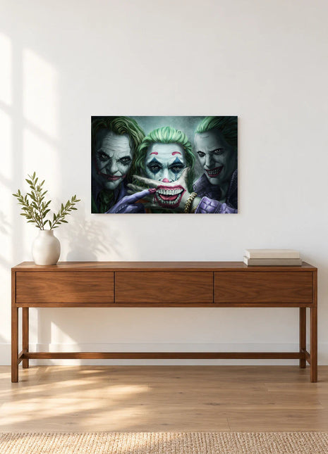 Joker Three Faces of Trouble acrylic wall art displayed above a wooden console with a leafy vase and stacked books against a white wall.