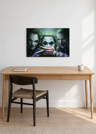Joker Three Faces of Trouble acrylic wall art displayed above a wooden desk with a notebook, pencil and white mug against a white wall.