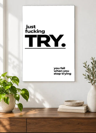 Just Try acrylic wall art displayed above a wooden console with plants and books against a white wall.