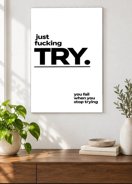 Just Try acrylic wall art displayed above a wooden console with plants and books against a white wall.