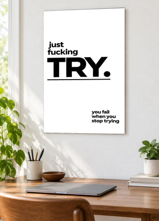 Just Try acrylic wall art displayed above a wooden desk with a laptop, plants and books against a white wall.