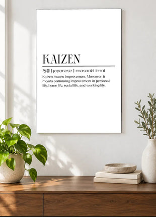 Kaizen Defined acrylic wall art displayed above a wooden console with plants and books against a white wall.