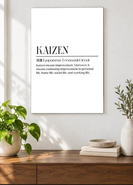 Kaizen Defined acrylic wall art displayed above a wooden console with plants and books against a white wall.
