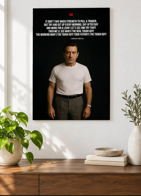 Lorenzo Anello Working Man acrylic wall art displayed above a wooden console with plants and books against a white wall.