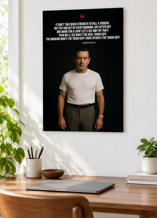 Lorenzo Anello Working Man acrylic wall art displayed above a wooden desk with a laptop, plants and books against a white wall.