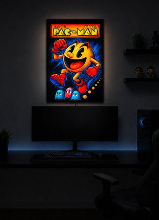 Pac-Man wearing red gloves and boots above three small ghosts, with arcade lettering across the top, illuminated in a slim black acrylic LED lightbox above a monitor in a dark game room.