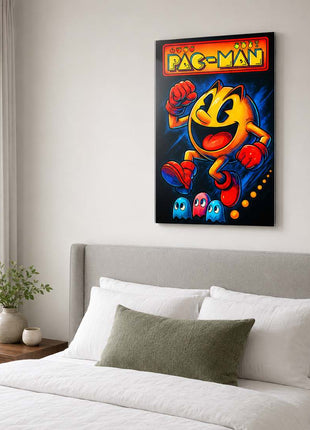 Pac-Man wearing red gloves and boots above three small ghosts, with arcade lettering across the top on acrylic wall art above a gray upholstered headboard in a bedroom with white bedding.