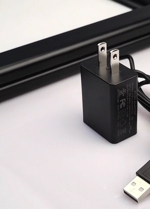 6ft USB power cable and included wall adapter shown next to the corner of the RGB LED acrylic lightbox frame, demonstrating the standard plug-and-play setup for Snapping Turtle Gallery frames.