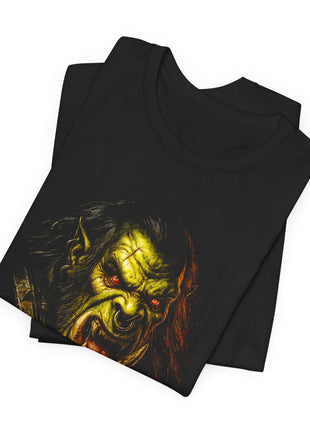 Folded black T-shirt close-up showing the orc’s red eyes, heavy brow, nose ring and upper tusks.