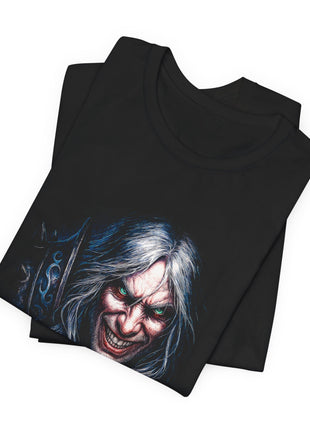 Folded black T-shirt close-up showing the warrior’s green eyes, toothy grin, silver hair and the blue decoration on a pointed weapon.