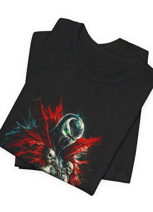 Folded black T-shirt close-up of Spawn’s mask, green eyes, jagged red collar and skull clasps.