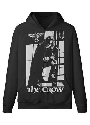 Front of a black The Crow zip-up hoodie showing Eric Draven crouched beside bright window panes, a crow emblem and white title lettering.