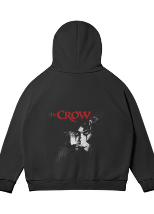 Rear view of the black The Crow Winged Shadow hoodie with the hood raised, showing the pale Eric Draven face, dark crow motif and red title lettering across the back.