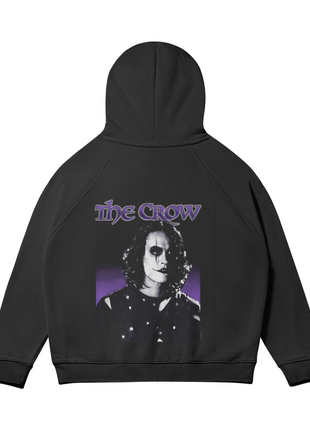 Rear view of the black The Crow Violet Shadows hoodie with the hood raised, showing the monochrome Eric Draven portrait, violet title lettering and purple backdrop across the back.