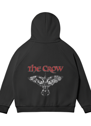 Rear view of the black The Crow Winged Eyes hoodie with the hood raised, showing the white-gray winged crow-and-eyes emblem and red title lettering across the back.