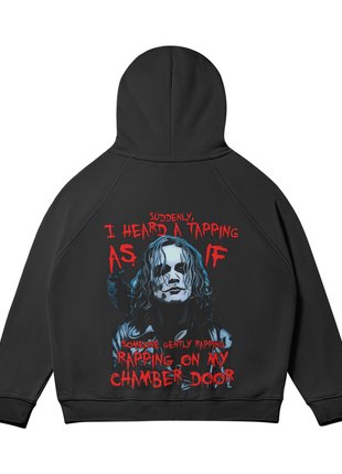 Rear view of the black The Crow Chamber Door hoodie with the hood raised, showing the blue-gray Eric Draven portrait and red chamber door quote lettering across the back.