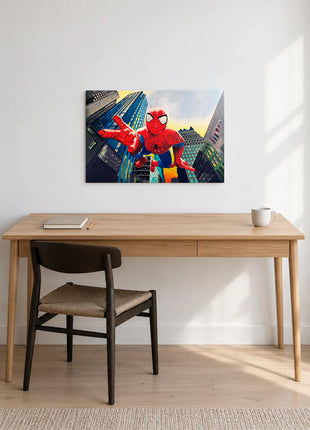 Spider-Man reaching toward the viewer between angled city buildings displayed above a desk in a room setting