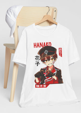 White Hanako-kun graphic T-shirt on a wooden hanger beside a chair.