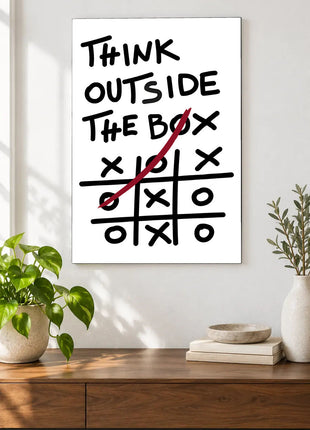 Win Outside the Lines acrylic wall art displayed above a wooden console with plants and books against a white wall.